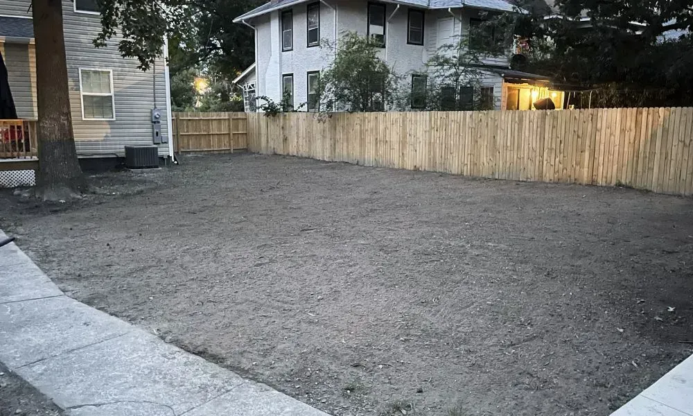 A clear lawn area outside a house undergoing professional yard leveling and landscape grading by a