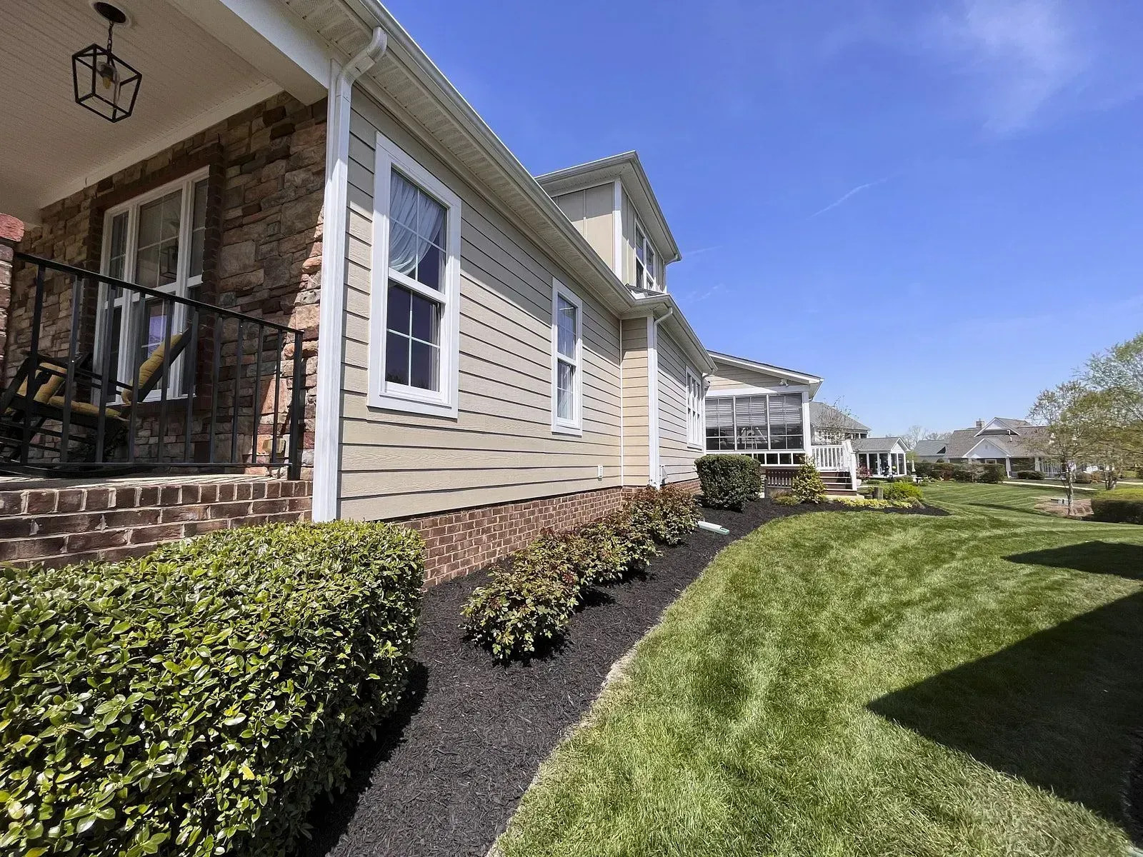 A house with a garden and its corners mulched along with ground level grass as a result of a professional mulch service