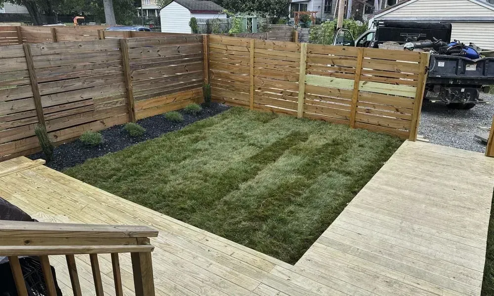 A small lawn area covered partially with wooden pathways and sod installation is working as the