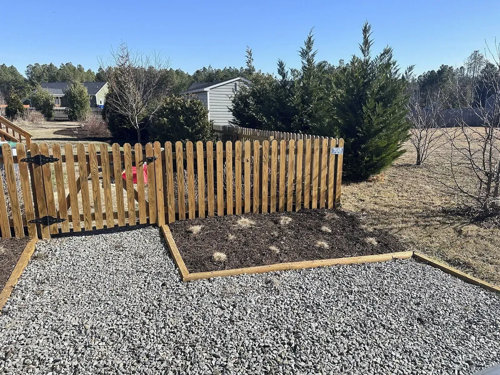 A small section within a lawn area with a wooden boundary wall is dug out for mulch installation