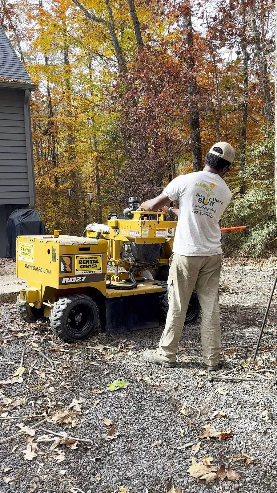Backshot of a professional stump grinder machine operator working for tree stump removal in the backyard