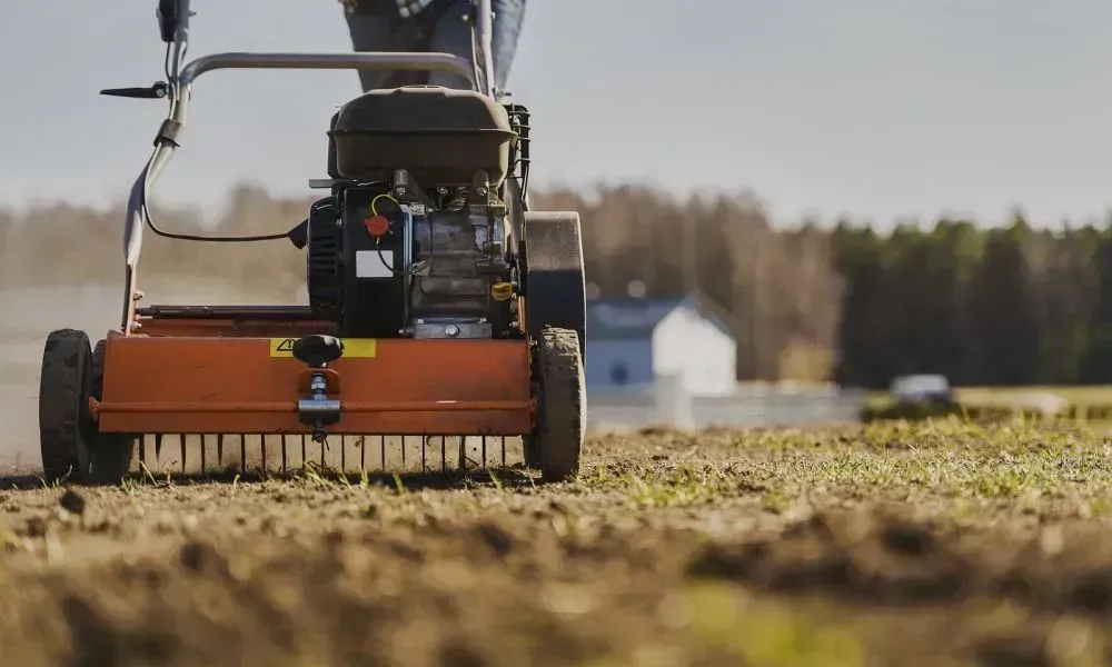 Closeup shot of the bottom of a lawn aeration machine working in a lawn with two small wheels and