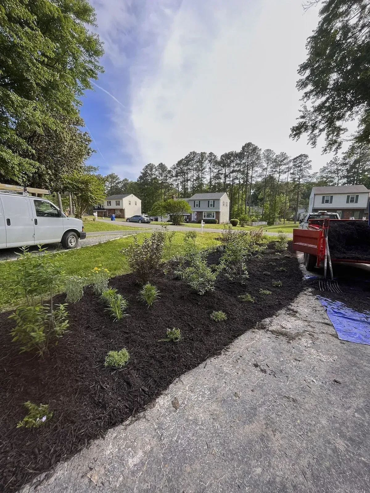Mulch installation with some plants added on a slope within a section of a big lawn