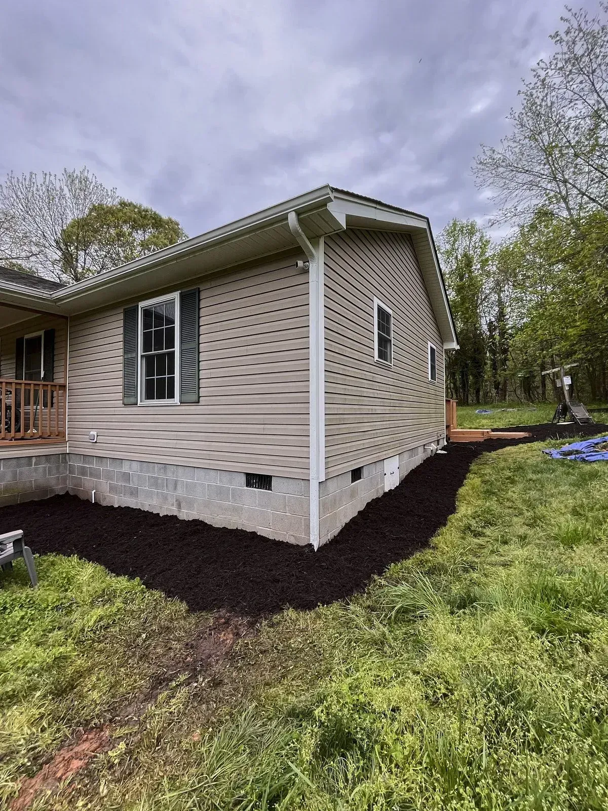 Wide angle shot of a small corner house with its foundation dug for mulch spreading for seeding and a big lawn area around