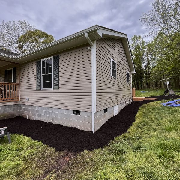 Wide Angle Shot Of A Small Corner House With Its Foundation Dug For Mulch Spreading For Seeding And A Big Lawn Area Around